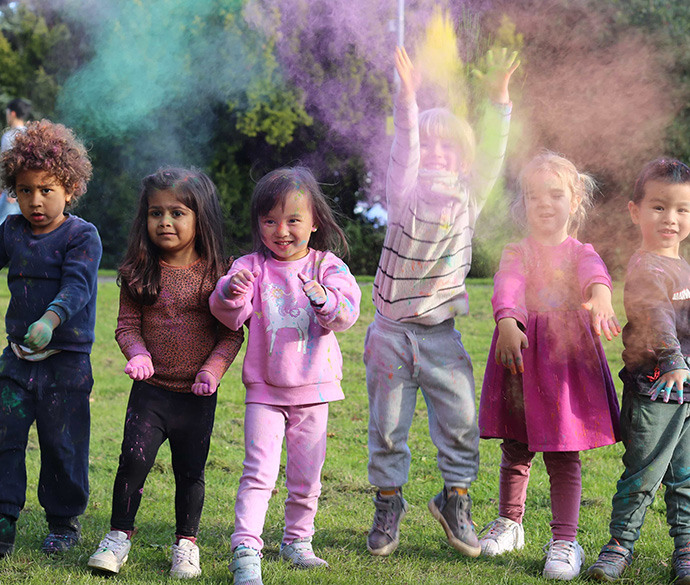 A group of children playing on a lawn with colourful powder.